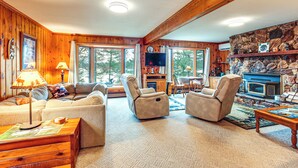 A cozy living room with a fireplace, comfortable seating, and large windows offering a view of the outdoors. - Outdoor Lover's Paradise w/ Dock & Fire Pit! (Woodruff)