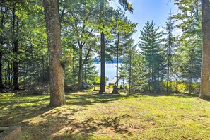 A forested area with a lake, picnic tables, and a small cabin. - Outdoor Lover's Paradise w/ Dock & Fire Pit! (Woodruff)