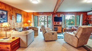 A cozy cabin interior with a sofa, two recliners, a wooden dining table, and a television. - Outdoor Lover's Paradise w/ Dock & Fire Pit! (Woodruff)