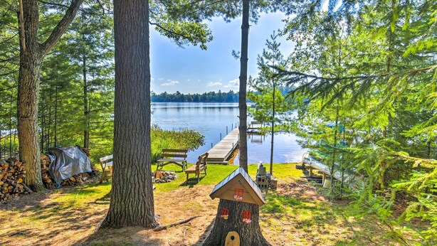 A lakeside campsite with a wooden deck, picnic table, and a birdhouse. - Outdoor Lover's Paradise w/ Dock & Fire Pit! (Woodruff)