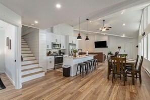 Una cocina moderna con armarios blancos, una isla central y taburetes de bar.