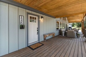 A covered porch with a wooden bench, a white door, and a number sign. - Welcome! 4 bedroom (6 bed) 3 bath River House (Sedalia)