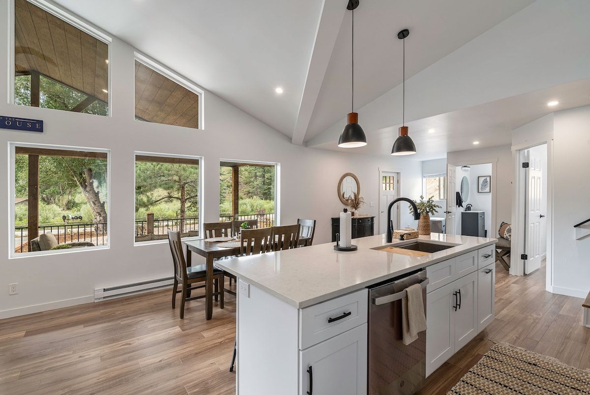 A modern kitchen with a large island, pendant lighting, and a view of the outdoors.