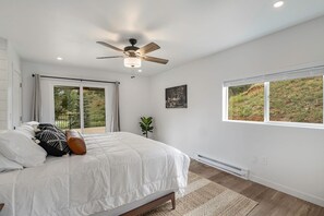 A bedroom with a bed, a ceiling fan, a window with a view, and a radiator. - Welcome! 4 bedroom (6 bed) 3 bath River House (Sedalia)