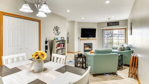 Een moderne woonkamer met een open haard, een eethoek met een tafel en stoelen, en een zithoek met banken.