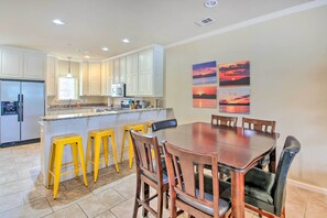 A kitchen with white cabinets, a refrigerator, a microwave, and a sink. There are yellow stools and a wooden dining table with chairs. - Balcony & Boat Slip: Lakefront Unit in Hot Springs (Hot Springs)