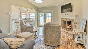 A living room with a fireplace, a television mounted above it, and a view of the outdoors through the glass doors.