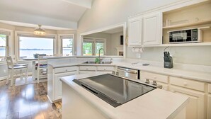 A modern kitchen with white cabinetry, a built-in microwave, and a large island with an induction cooktop.