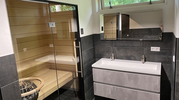 Un bany modern amb dutxa de vidre, un lavabo gran i un mirall a sobre.