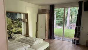 Un dormitori amb dos llits, un armari i vista a un jardí per una porta corredissa.