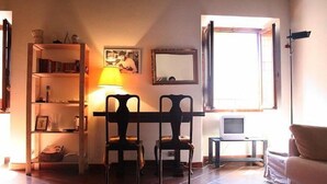 A room with a wooden desk, two chairs, a bookshelf, a lamp, a small TV, and a window. - Portico d'Ottavia, heart of ancient Rome (Roma)