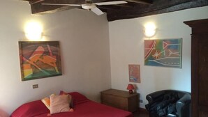 A bedroom with a bed, a chair, and two paintings on the wall. - Portico d'Ottavia, heart of ancient Rome (Roma)