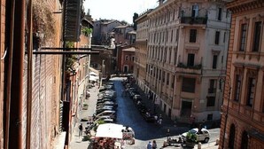 A narrow street lined with parked cars and buildings on both sides. - Portico d'Ottavia, heart of ancient Rome (Roma)