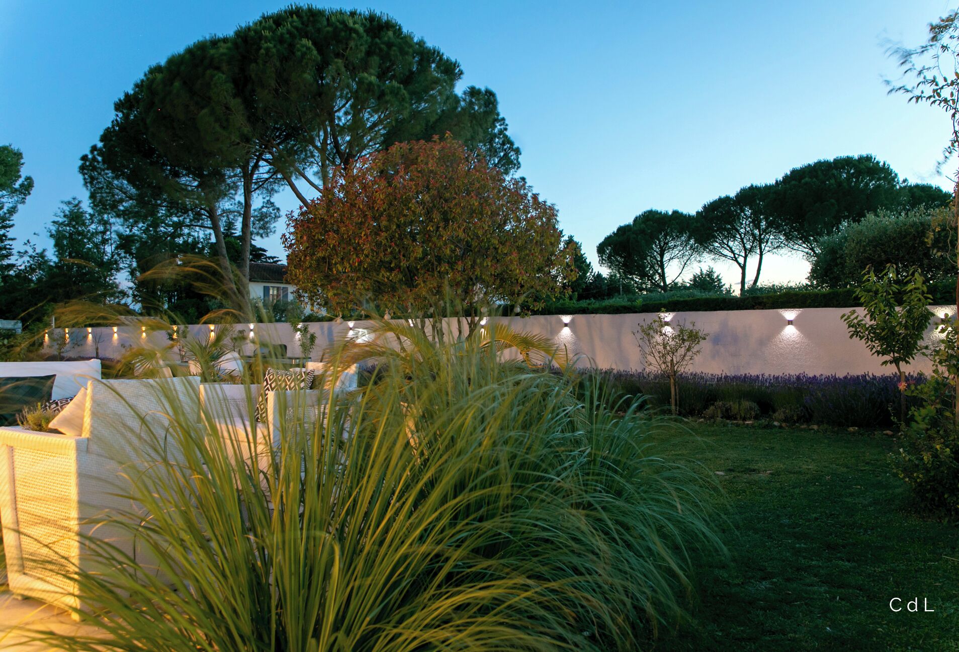 A landscaped garden with a wall, trees, and a grassy area.