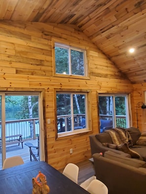 A cabin interior with wooden walls, a dining table, and a sofa.