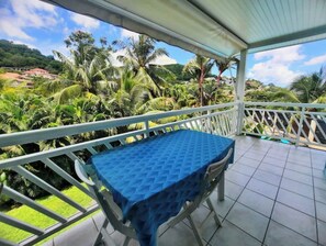 Enjoy a tranquil retreat with a balcony overlooking lush tropical gardens and palm trees.