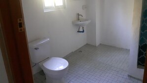 Ett litet, rent badrum med toalett, handfat och fönster.