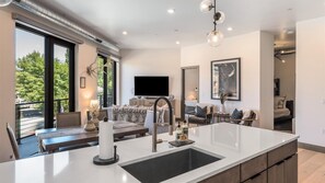 A modern kitchen with a large island, built-in appliances, and a dining area with a view of the outdoors. - New Listing! The River's Edge Condo- Brand New Condo in the Heart of Whitefish (Whitefish)