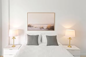 A bedroom with a bed, two bedside tables with lamps, and a framed picture on the wall. - Seascape: Luxury Waterfront Living in the Heart of Cairns (Cairns City)