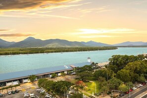 Vista costera con un puerto deportivo, montañas al fondo y un edificio con el número '3' en el techo.