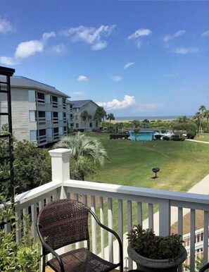 Relax on the balcony with a serene view of the well-maintained lawn and pool.