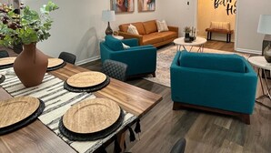 Ein modernes Wohnzimmer mit einem Holzesstisch, blauen Sofas und einem Deckenventilator.