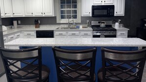 A modern kitchen with white cabinets, a black microwave, and a granite countertop.