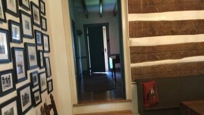 A room with a wooden staircase leading to a door, a chessboard on a table, and a wall with framed pictures.