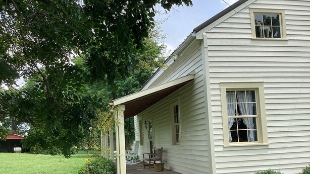 A single-story house with a porch, a small garden, and a visible window.