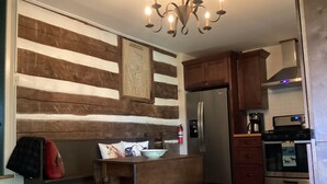 A kitchen with wooden paneling, a stainless steel refrigerator, a microwave, and a stove.
