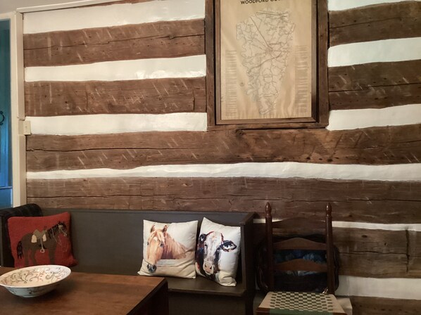 A room with a rustic wooden wall, a map, a wooden chair, and a table with a bowl.