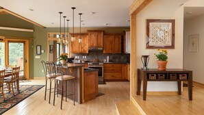 A spacious kitchen with wooden cabinets, a central island, and pendant lighting. - Spacious 4 BR mountain home with pool table, hot tub, and incredible views (Golden)