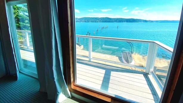 Una habitación con un ventanal que da a una terraza de madera y una masa de agua.
