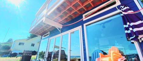 A house with a large glass door, a barbecue grill outside, and a pool area.