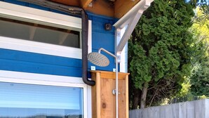 Un cerramiento de ducha de madera adosado a una casa azul con una ventana.