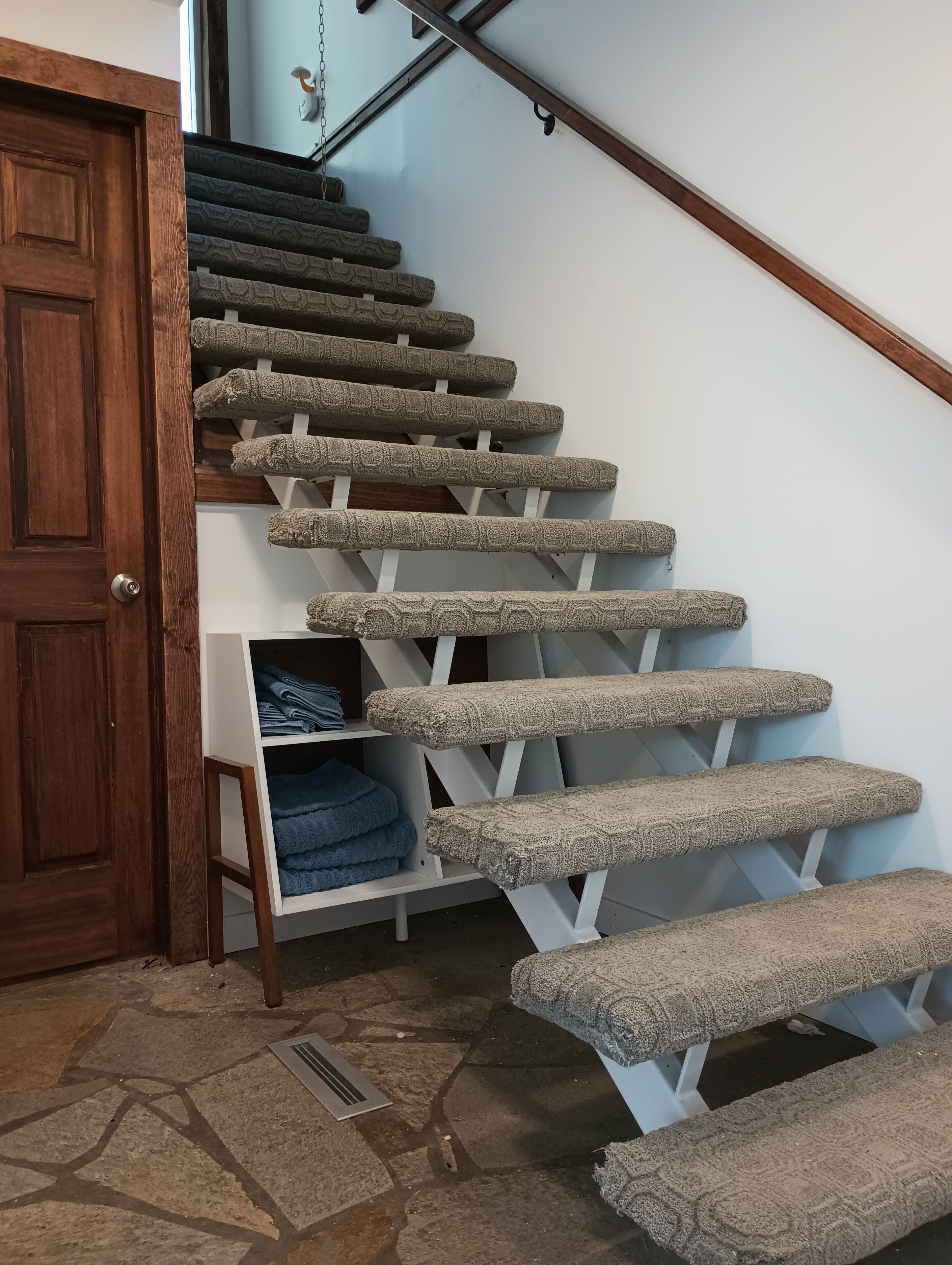 Un escalier dont les marches sont recouvertes de moquette et une porte en bois.