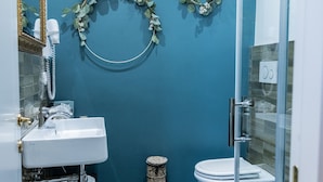 A bathroom with a blue wall, a white sink, a toilet, and a shower area. - TRESCA CHARME ROOM 22  (Bari)