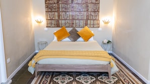 A bedroom with a bed, two bedside tables, a wall-mounted light fixture, and a patterned floor. - TRESCA CHARME ROOM 22  (Bari)