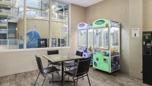 Zona pranzo con tavolo in vetro e sedie, distributori automatici e vista su un edificio con balconi.