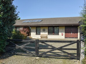 A stable with a wooden gate, a bench, and a solar panel on the roof. - 3 bedroom accommodation in Crackington Haven, near Bude (Crackington Haven, near Bude)