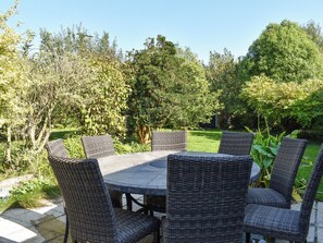 A round outdoor table with wicker chairs, surrounded by lush greenery and trees. - 3 bedroom accommodation in Crackington Haven, near Bude (Crackington Haven, near Bude)