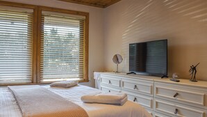 A bedroom with a bed, a TV, a dresser, and a window with blinds. - 3 bedroom accommodation in Crackington Haven, near Bude (Crackington Haven, near Bude)