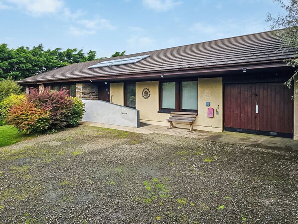 A building with a sloped roof, a bench outside, and a gravel driveway. - 3 bedroom accommodation in Crackington Haven, near Bude (Crackington Haven, near Bude)