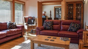 A living room with two leather sofas, a wooden coffee table, and a door leading to another room. - 3 bedroom accommodation in Crackington Haven, near Bude (Crackington Haven, near Bude)