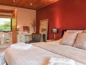 A bedroom with a bed, a chair, a bedside table with a lamp, a mirror, and a window. - 3 bedroom accommodation in Crackington Haven, near Bude (Crackington Haven, near Bude)