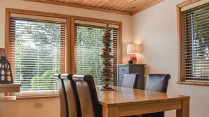 A dining area with a wooden table, chairs, a lamp, and a decorative rock wall. - 3 bedroom accommodation in Crackington Haven, near Bude (Crackington Haven, near Bude)
