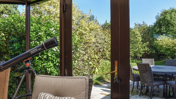A telescope, a cushioned chair, and a dining table in a covered outdoor area. - 3 bedroom accommodation in Crackington Haven, near Bude (Crackington Haven, near Bude)
