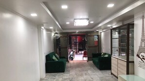 Un interior modern amb dos sofàs verds, una vitrina de cristall i un paviment de rajoles.