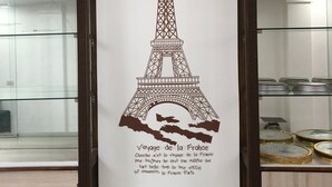 Paret amb un dibuix de la Torre Eiffel i text en francès.