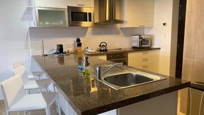 Una cucina moderna con piano di lavoro in granito, lavello in acciaio inossidabile e mobili bianchi.